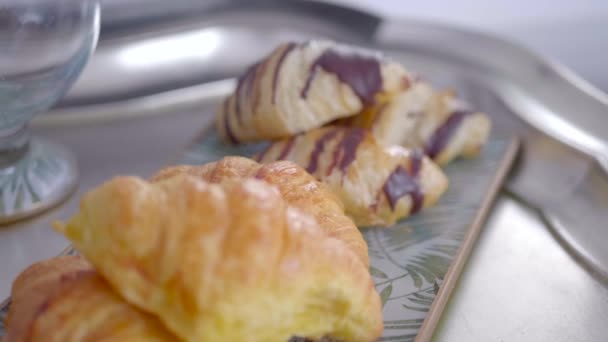 Chocolate bakery products called mini napolitana and croissants on a metal tray with coffee for breakfast. Sweet snack. - Materiał filmowy, wideo