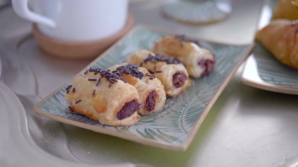 Chocolate bakery products called mini napolitana and croissants on a metal tray with coffee for breakfast. Sweet snack. - Video, Çekim