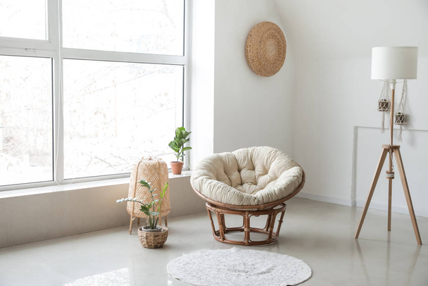 Wygodny fotel z lampami i roślinami w pobliżu ściany światła w pokoju - Zdjęcie, obraz
