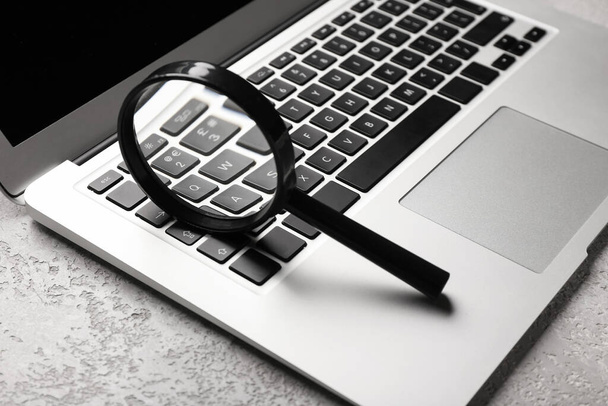 Laptop and magnifier on light background. Concept of search - Foto, imagen