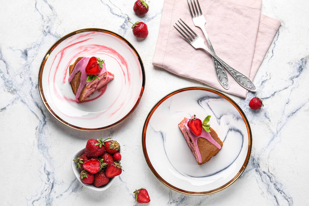 Composition with plates of tasty strawberry cake and berries on light background - 写真・画像
