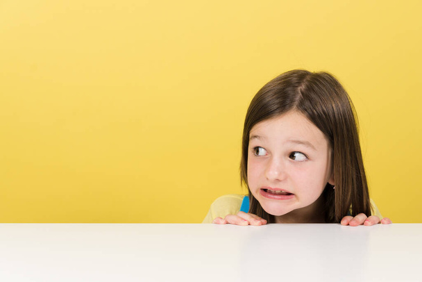 Closeup portrait of scared little girl looking at yellow copy space - Fotoğraf, Görsel