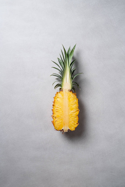 Top view of fresh cut pineapple with tropical leaves on dark blue background. - Foto, afbeelding
