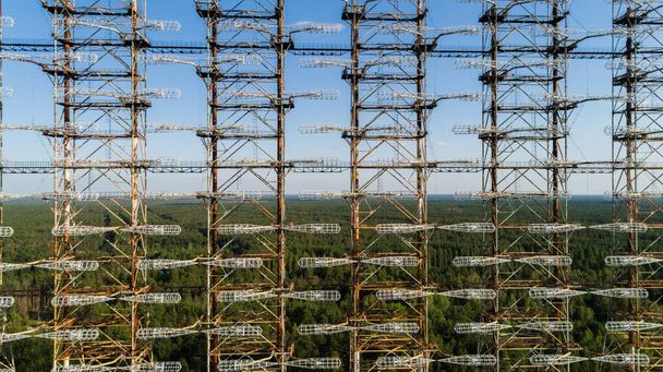 Close up aerial view of the DUGA radar station near the city of Chernobyl-2 among the forest in sunny day. Drone shot Chernobyl exclusion zone in summer. Radiation - 写真・画像
