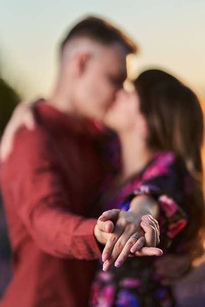 Young happy couple showing the engagement ring at sunset in a lavender field - 写真・画像