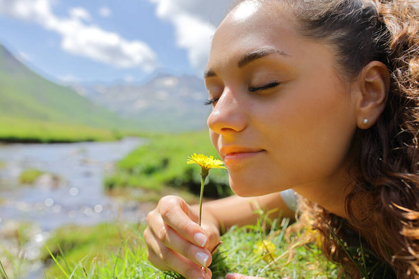 Portrait of a woman smelling a flower in the mountain in a riverside - Foto, imagen