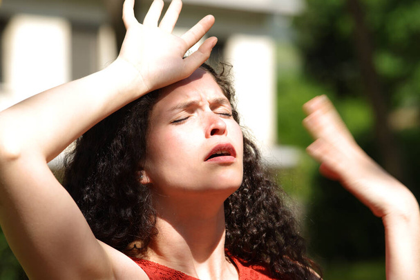 Overwhelmed woman suffering heat stroke a sunny day in a park - Фото, изображение