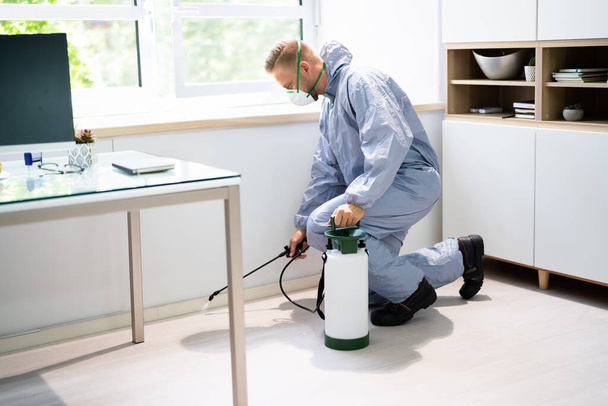 Exterminateur de lutte antiparasitaire Pesticide termite pulvérisé par l'homme au bureau - Photo, image