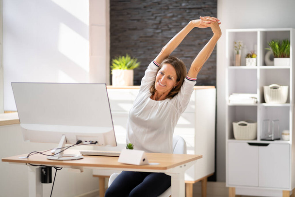 Woman Stretches At Office Desk. Stretch Exercise On Chair - Foto, Imagen