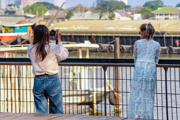 Powrót widok portret atrakcyjne azjatyckie kobiety podróżnik zrobić zdjęcie aparatem cyfrowym razem nad brzegiem rzeki podczas weekendowej podróży. Szczęście i przyjaźń przyjaciółek. Atrakcje turystyczne i koncepcja podróży - Zdjęcie, obraz
