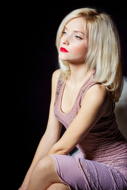 Portrait of a beautiful sexy women blonde with red lipstick and arrow keys on the eyes in a pink dress in the Studio - Foto, imagen
