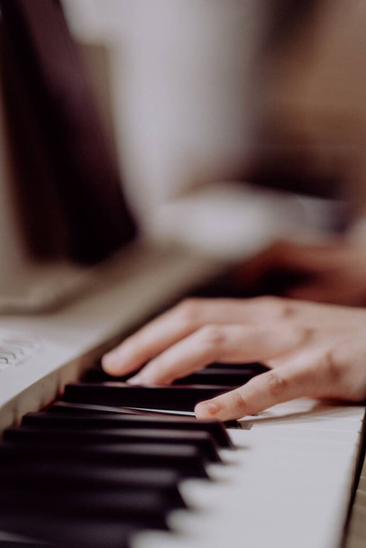 A closeup of a hand on a piano keyboard with a blurry background - Zdjęcie, obraz