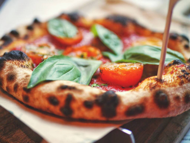 A closeup shot of an Italian pizza on the wooden background - Fotoğraf, Görsel