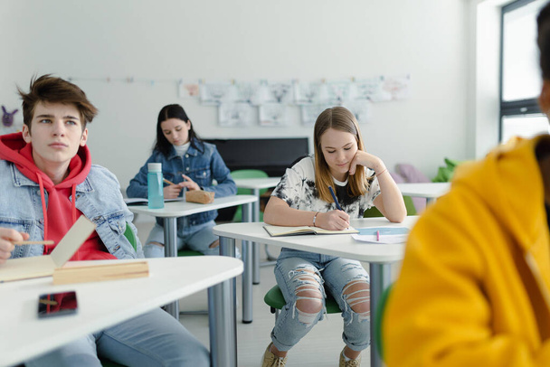 High school students paying attention in a class, sitting in their desks and writing notes, back to school concept. - 写真・画像