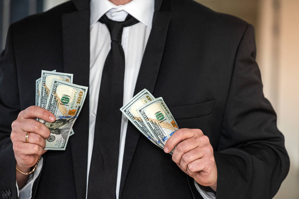 У центральному офісі бос у шикарному костюмі бере долари з власної кишені. Концепція боса з грошима
 - Фото, зображення
