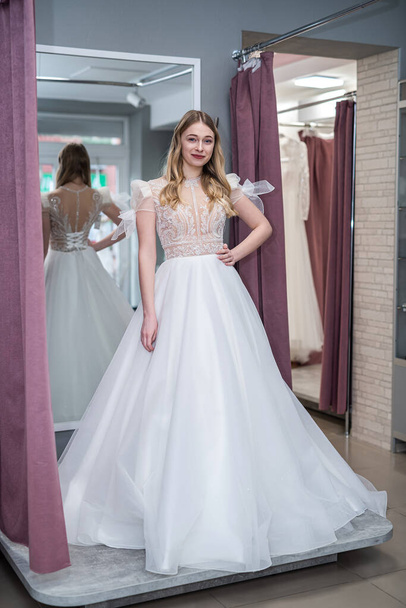 young prety woman is trying white wedding dresses in shop - Foto, Imagem