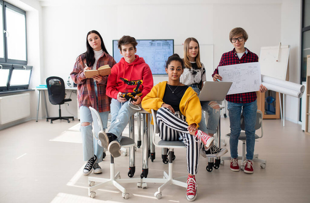 Group of students sitting and posing together in a robotics classroom - Photo, image