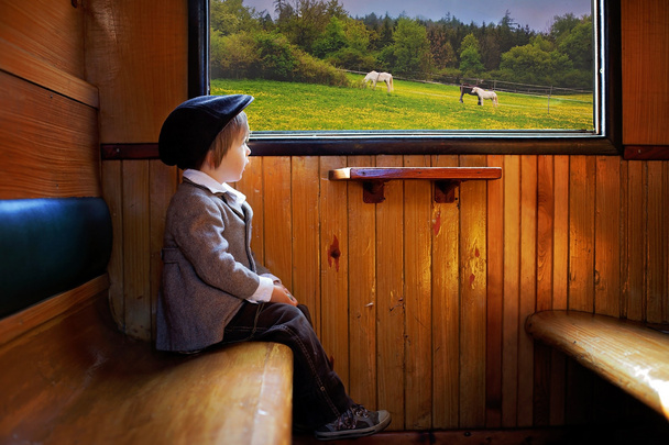 Boy, dressed in vintage coat and hat, sitting in a train - Φωτογραφία, εικόνα