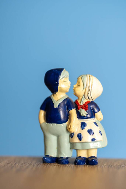The vertical shot of a Dutch kissing couple figurine standing on a wooden surface - Foto, immagini