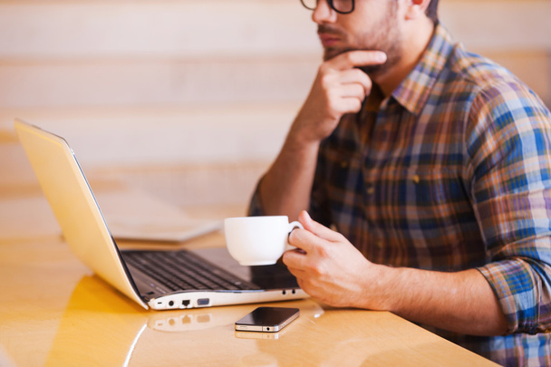 Man working on laptop and drinking coffee - Photo, Image