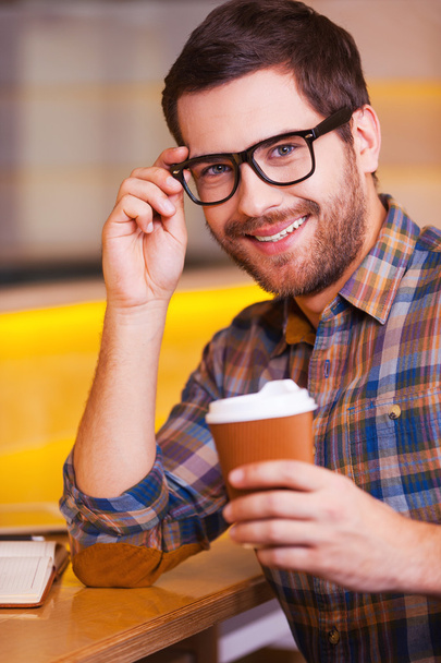 Man holding coffee cup and adjusting eyeglasses - Foto, Bild
