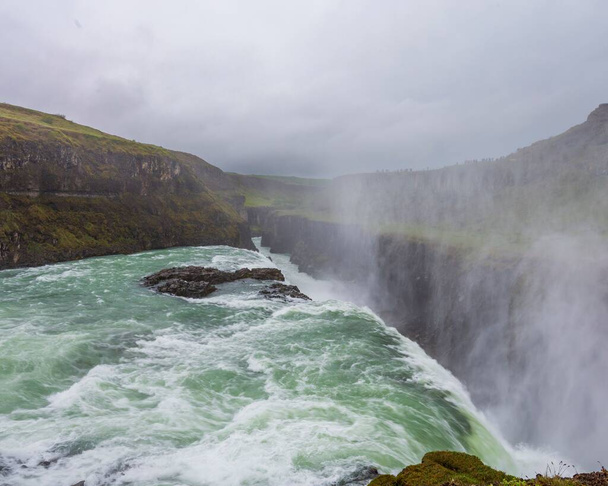 A scenic view of Gullfoss Falls waterfall in Iceland in a rural area in cloudy sky background - Zdjęcie, obraz