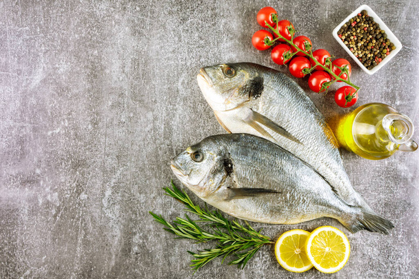 Fresh fish dorado and ingredients for cooking. Raw fish dorada with spices and herbs on gray concrete table. Seafood, restaurant, diet, healthy food background. Top view, flat lay with copy space - Foto, Imagem