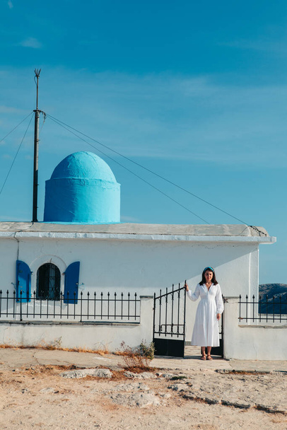 beautiful woman in white dress near old greece church white with blue - Valokuva, kuva