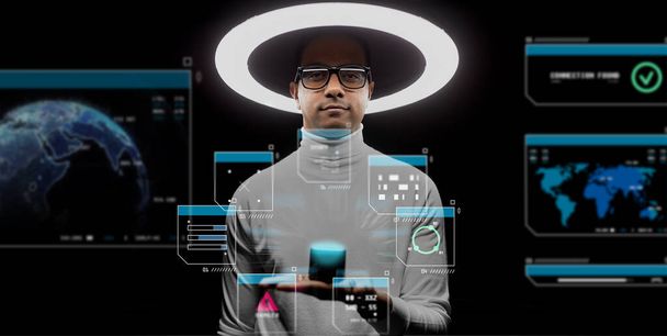 future technology and virtual reality concept - man in glasses with smart speaker under white illumination and hologram on black background - Foto, Imagen