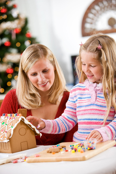 Christmas: Mother And Girl Decorating Gingerbread House Together - Фото, зображення
