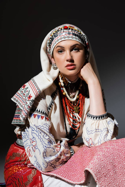 retrato de mujer ucraniana joven en ropa tradicional con adorno y cuentas rojas en negro - Foto, imagen