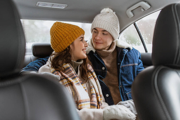people, love and leisure concept - happy smiling couple hugging on car back seat in winter - Photo, image