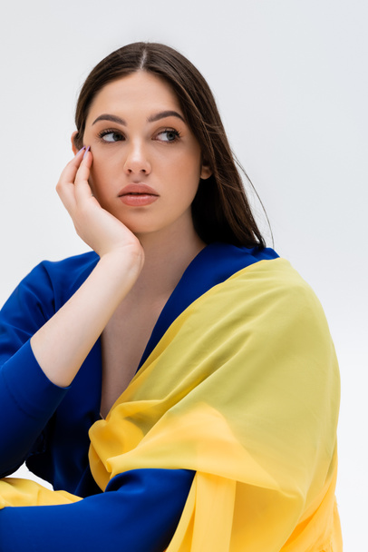 dreamy ukrainian young woman in blue and yellow outfit looking away isolated on grey - Valokuva, kuva