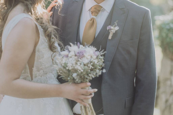 A closeup of a  bride in white wedding dress holding bouquet with a groom in suit - Zdjęcie, obraz