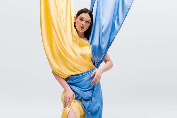 young ukrainian woman in blue and yellow dress standing isolated on grey - Fotó, kép