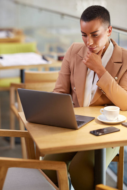 Une femme d'affaires concentrée dans un café prépare la documentation sur l'ordinateur portable. - Photo, image