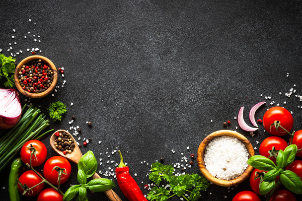 Food background on black stone table. Fresh vegetables, herbs and spices. Ingredients for cooking with copy space. - Photo, image
