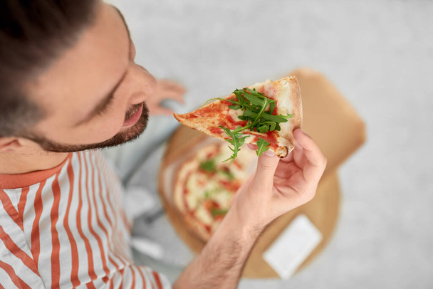 food delivery, consumption and people concept - close up of happy man eating takeaway pizza at home - Foto, imagen