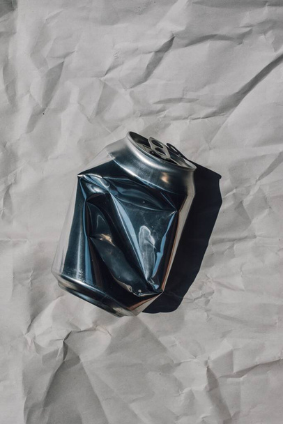 crumpled paper with hand shadow and crumbled crushed aluminum can recycling - Zdjęcie, obraz