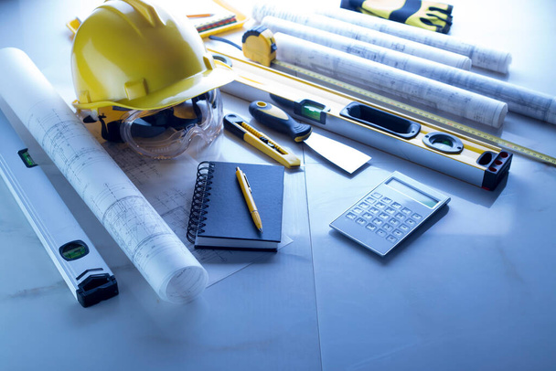 Contractor theme. Plans,  notebook and tool kit of the contractor: yellow hardhat, libella and yardstick.  - Foto, Imagen