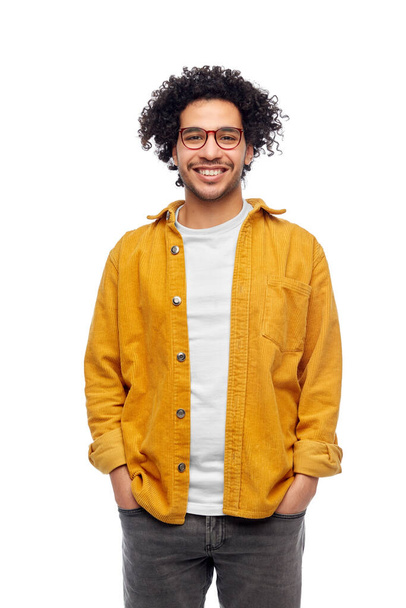 people and fashion concept - happy smiling man in glasses and yellow jacket with hands in pockets over white background - Photo, image