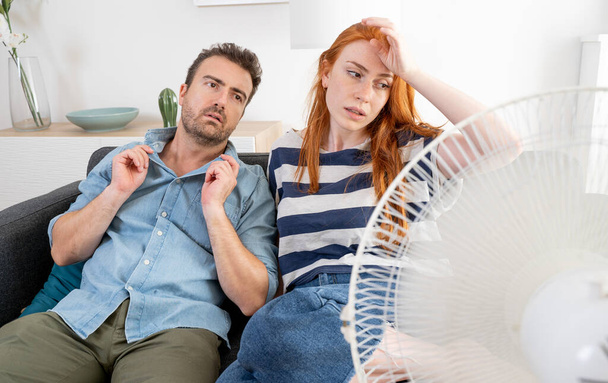 Young couple suffering summer heat wave at home - Foto, afbeelding