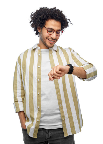 technology and people concept - smiling young man in glasses with smart watch over grey background - Foto, imagen