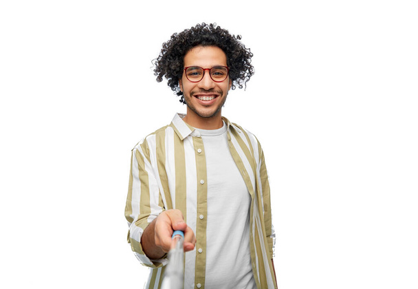 people concept - happy smiling young man in glasses taking picture with selfie stick over white background - Foto, immagini