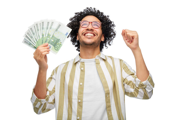 finance, currency and people concept - happy man holding hundreds of euro money banknotes celebrating success over white background - Fotoğraf, Görsel