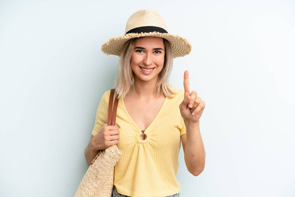 blonde woman smiling and looking friendly, showing number one. summer concept - Foto, imagen