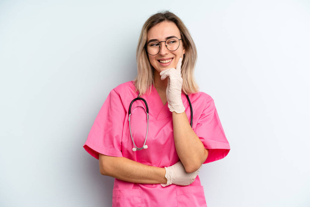 blonde woman smiling with a happy, confident expression with hand on chin. nurse concept - Foto, immagini