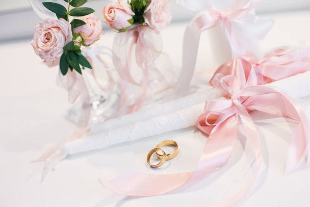 Gold wedding rings lie on the table near the wedding candles. Beautiful wedding background. Wedding details, symbol of love and marriage. - Photo, Image