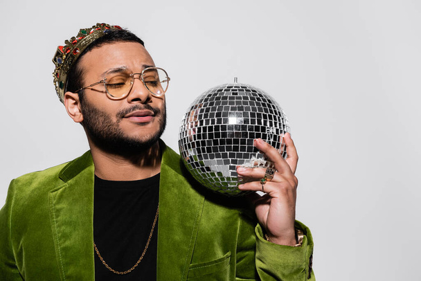eastern hip hop performer in green velvet blazer and crown holding disco ball isolated on grey - Foto, immagini