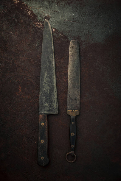 rustic set of kitchen knife and knife sharpener with wooden handle and carbon steel blade on top of rusty metallic background, food and cooking concept, flat lay - Photo, Image